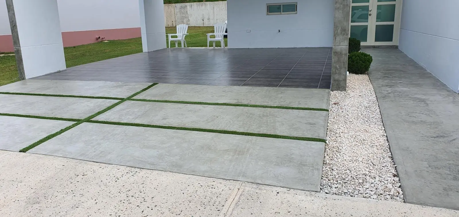 Entrada residencial en cemento pulido con líneas de grama